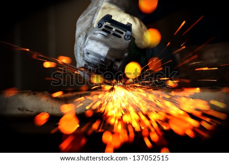 Worker cutting metal with a metal grinding sparks and bokeh Worker cutting metal with a metal grinding sparks and bokeh