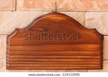 blank wooden signboard hanging on sandstone