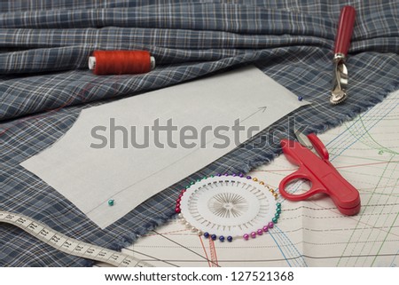 Metal scissors, threads, measuring tape, pins on tissue.