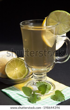 Green ice tea with lime and mint on a black background.