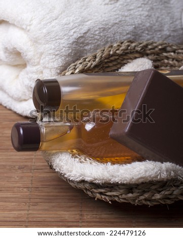 Chocolate soap, body oil, shampoo, body wash   in a basket and towel nearby.