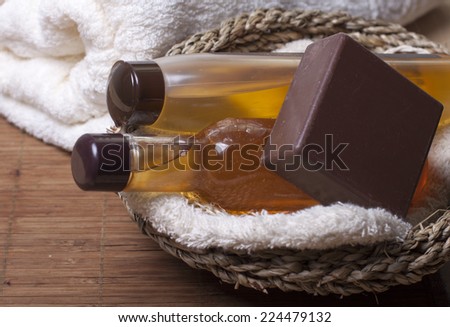 Chocolate soap, body oil, shampoo, body wash   in a basket   and   towel nearby.