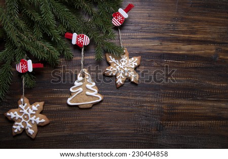 Christmas background with cookies decorated with icing, gloves and spruce branches on a wooden board.