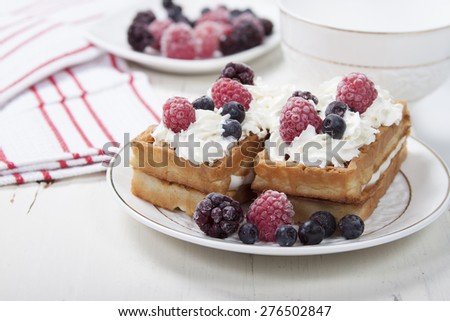 Soft waffles with protein cream, berry jam, whipped cream and berries.