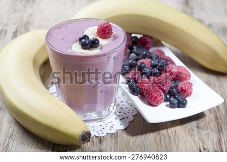 Smoothies of frozen raspberries, blueberries and banana with yogurt. Blueberries and raspberries on a white plate and a banana  on a wooden table. raspberries