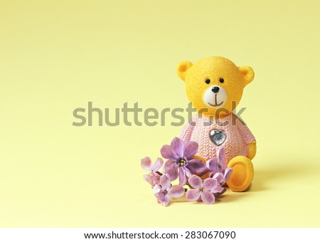 Teddy bear with a heart and lilac flowers. Space for text.