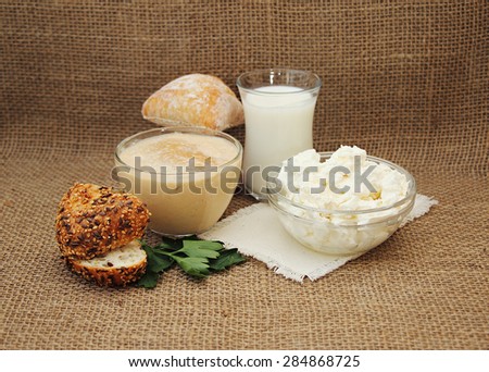 Fresh dairy products: milk, cottage cheese and fermented baked milk. Still life with fresh dairy products and grain bread on the background of burlap.