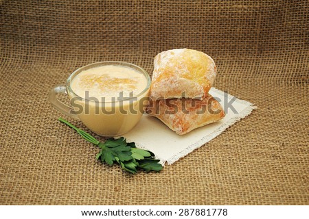 Fermented baked milk with foam, whole grain bread and parsley. Still life on the background of burlap.