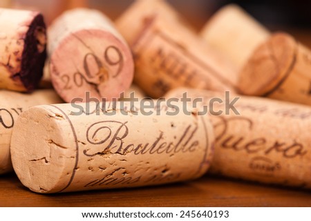 Close-Up of several Wine Corks on wood. You can read \