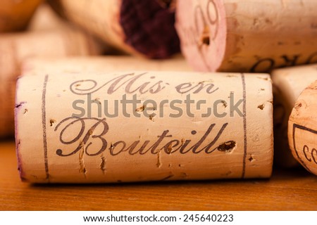 Close-Up of several Wine Corks on wood. You can read \