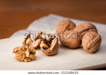 Close-up of Walnuts on a wooden board, one nut is cracked open.