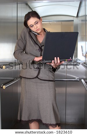 Business woman on cell phone with computer in lift