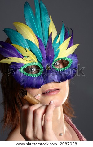 Model with feather mask smoking a cigar and looking at the camera