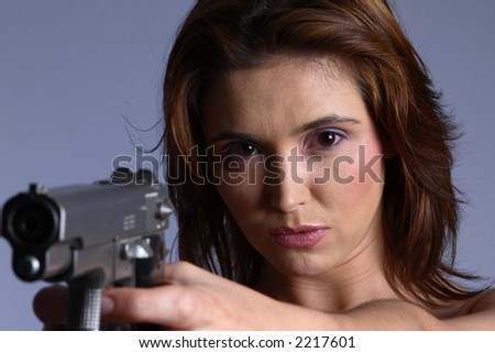Sexy brunette model with gun pointing at camera.