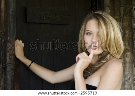 Beautiful blond teenager knocking on old dark wooden door