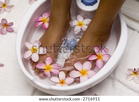 Woman with feet in a foot bath filled with water and flowers