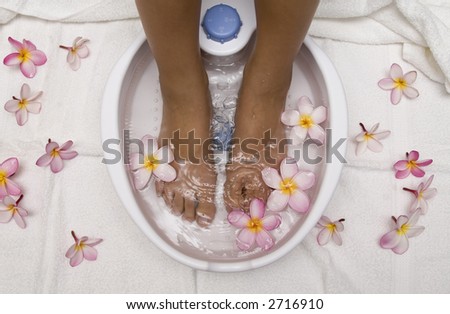 Woman with feet in a foot bath filled with water and flowers