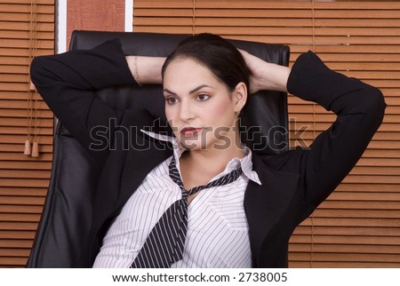 Brunette business woman with black suit leaning back in chair