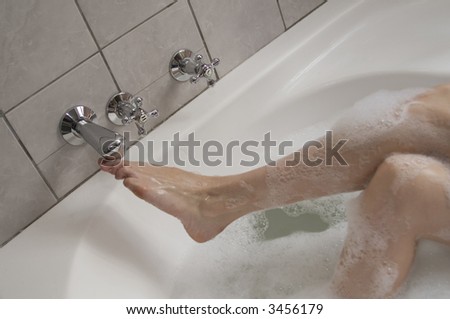 Woman\'s boot adjusting the water supply tap in a bubble bath