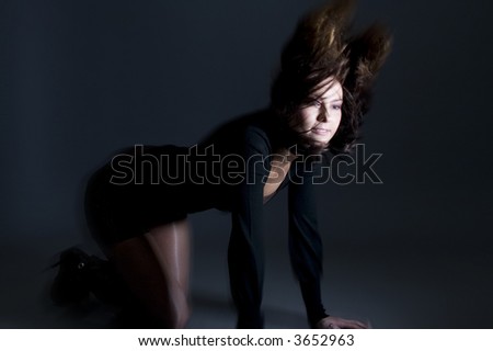 Attractive brunette on her knees wearing a black dress throwing hair back