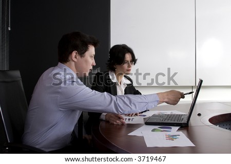 Business workgroup interacting in a boardroom setting with laptop