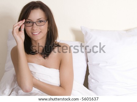stock photo Attractive brunette naked on a white linen bed with glasses on