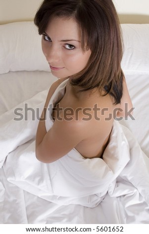 stock photo Attractive brunette naked on a white linen bed showing her 
