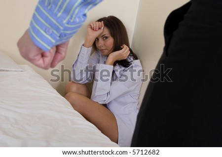 Mans fist showing with scared woman in the corner of room