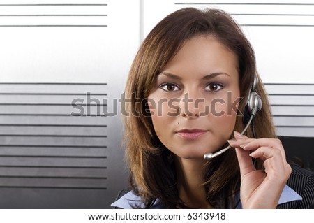 Young brunette call center agent talking on the headset in a modern office setting
