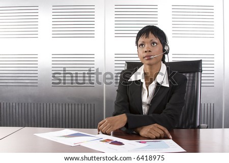 Young attractive african call center agent talking on the headset in a modern office setting