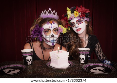 Day of The Dead girls in costume and make up celebrating birthday with cake