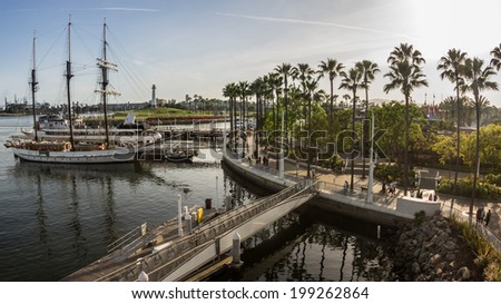 Boats docked and people in motion at Rainbow Harbor in Long Beach, California