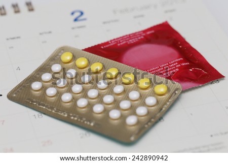 birth control pills and condom on a calendar