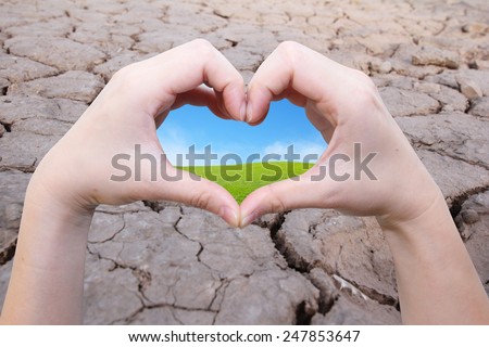 background of hand in heart shape with green field inside on the crack earth