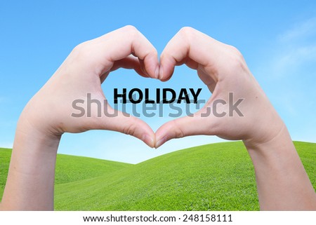 female hand in heart shape with  the words holiday on the green field