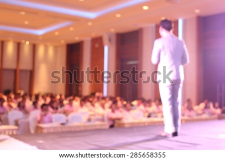 blurred image of businessman giving a speech on the stage