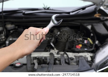 hand with wrench on car engine background