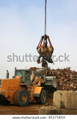 Bulldozer pushing scrap metal for the grab to pick up