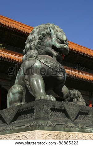 A gate at the Forbidden City in Beijing, China. In front is one of the two bronze lions that guards the entrance. Always a male and a female lion, the male with the ball of wisdom under its paw.