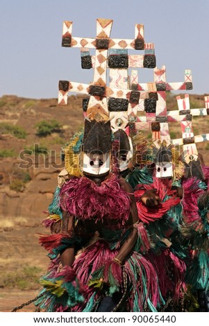 Masked Dogon dancers in a row, performing a ritual dance, wearing so-called kanaga-masks