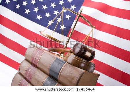 Scales of justice, gavel, stack of old law books with the American Flag in the background
