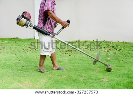 Man using string trimmer cutting grass in garden