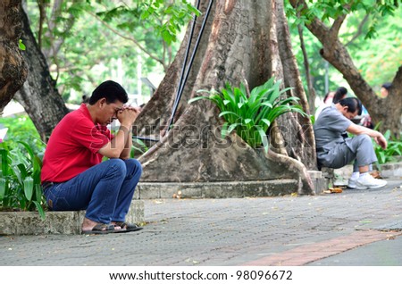 BANGKOK,THAILAND - MARCH 18: Father pray for his son to get in a 120 person from 4,200 challenger entrance exam for Satitpatumwan School, the best school in Thailand  . March 18, 2012 in Bangkok.