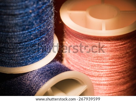 A macro shot of three reels of cotton thread.