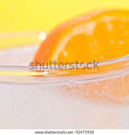 A slice of orange and a glass of fizzy water.