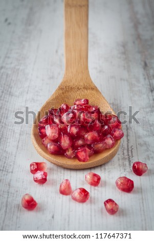 Grains of fresh pomegranate on a wooden spoon