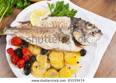 Delicious grilled gilt-head fish served with potatoes and tomatoes