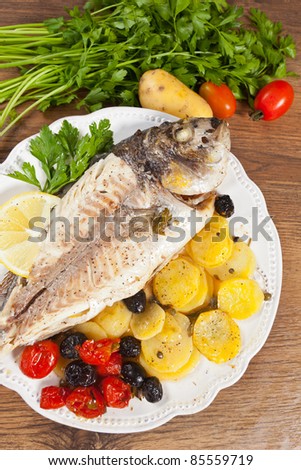 Delicious grilled gilt-head fish served with potatoes and tomatoes