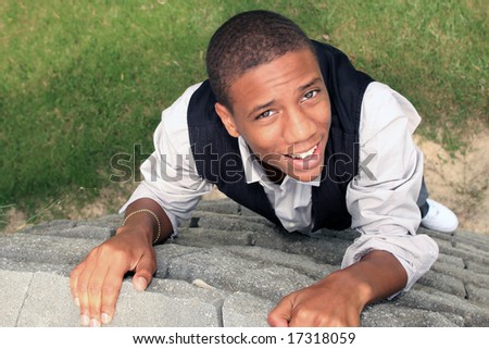 Man looking up smiling as he climbs wall