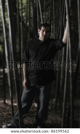 A man standing in a dark bamboo forest